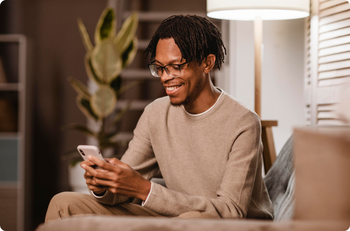 homem usando um aparelho celular moderno enquanto esta no sofa em casa